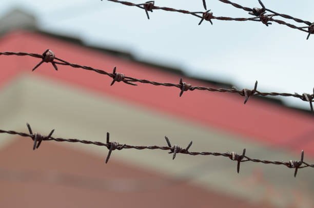 istock barbed wire with blur house background 2151622400