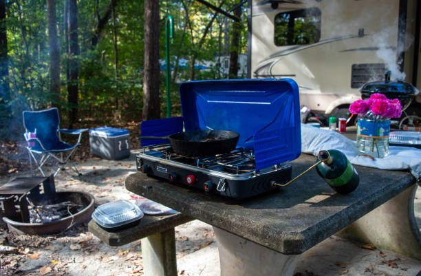 A small portable propane gas two burner stove serves as a convenient source of heat for outdoor cooking at the camp site in the beautiful state of Arkansas. Bokeh.