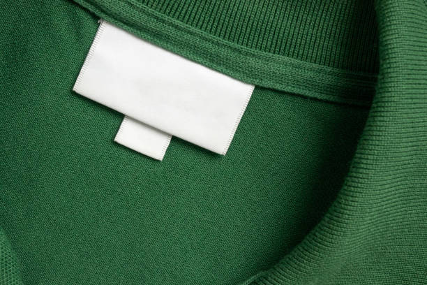 istock Blank white laundry care clothes label on green shirt fabric texture background 2151624606