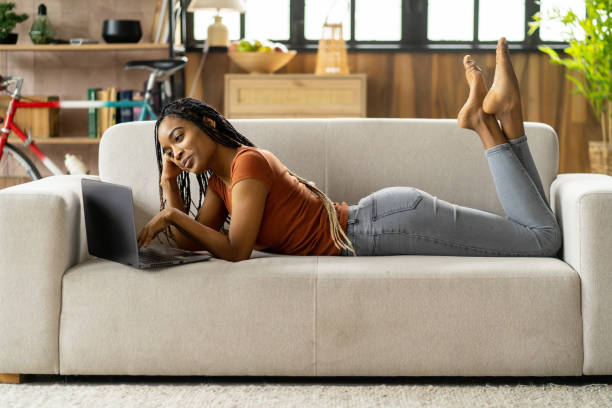 istock A young girl is laying on sofa and using a laptop 2151625315