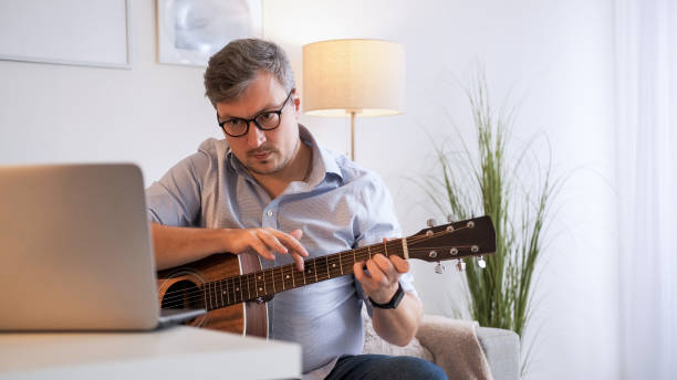 istock Guitar training video call man playing laptop home 2151625418