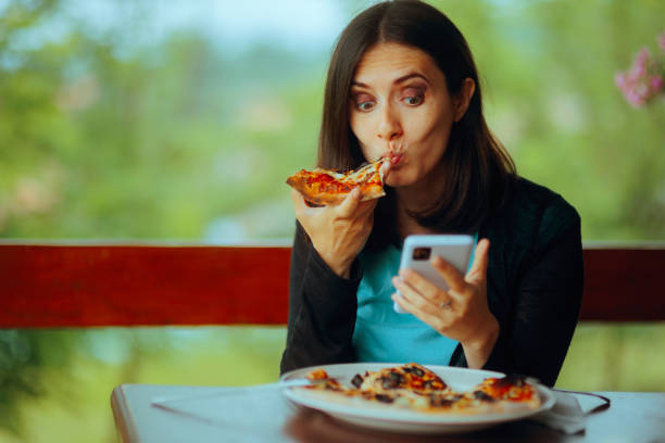 istock Woman Eating a Pizza while Checking her Phone 2151642692