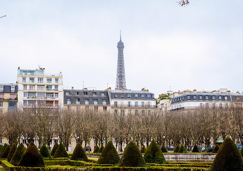 A quintessential Parisian scene unfolds as the Eiffel Tower rises majestically amidst the cityscape, offering a stunning view from the nearby park