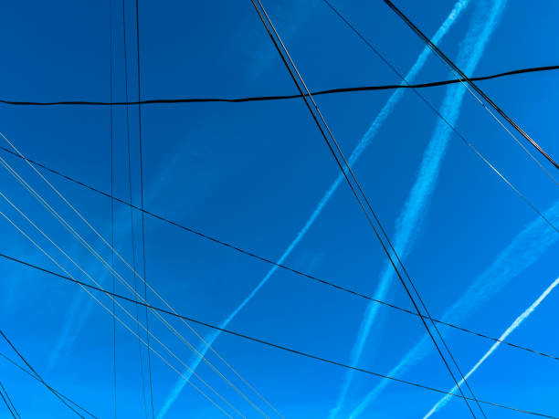 Pattern of airplane contrails and electrical wires over blue sky in spring as background