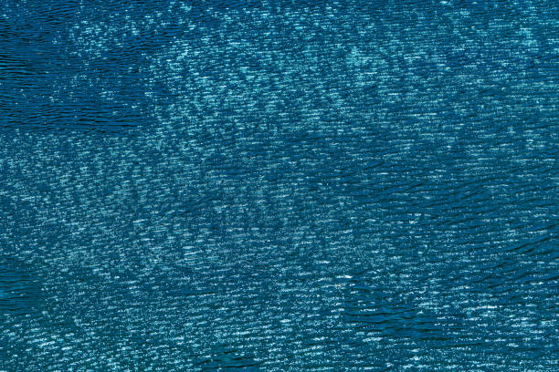 An abstract artistic scene of a wave breaking underwater in dramatic light. Photographed with slow shutter in camera technique.