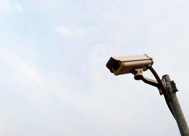 istock White surveillance camera or security CCTV or Close Circuit Television with installed on steel pole outdoor and monitor and record for property protection with white sky background and copy space. 2151653522