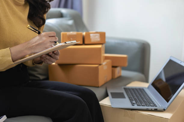 istock Small business startup, SME owner, female entrepreneur working on receipt boxes and checking online orders, laptop to prepare to pack boxes to sell to customers. Close-up photo 2151655849