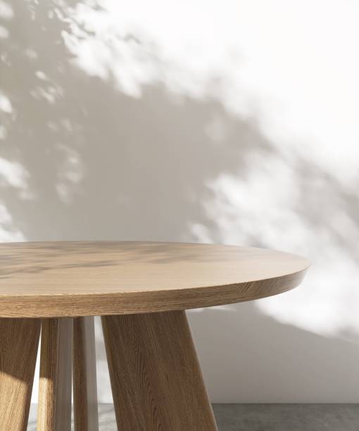 istock Round wooden table podium in dappled sunlight, tree leaf shadow on white wall 2151655891
