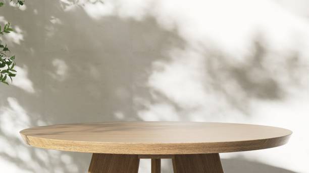 istock Round wooden table podium in dappled sunlight, tree leaf shadow on white wall 2151655894