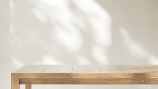 istock Minimal wooden counter table in dappled sunlight, leaf shadow on beige cream wall 2151655956
