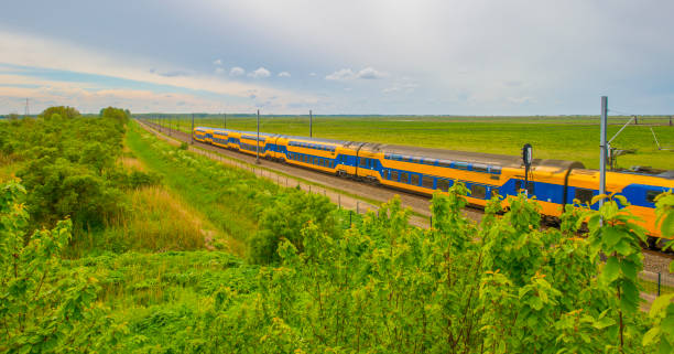 istock Train riding on a railroad track in wetland below a blue cloudy sky in springtime 2151662378