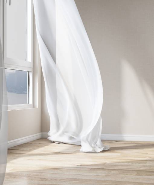 Empty room with cream wallpaper wall, blowing white sheer curtain in sunlight from window, tree shadow on parquet floor