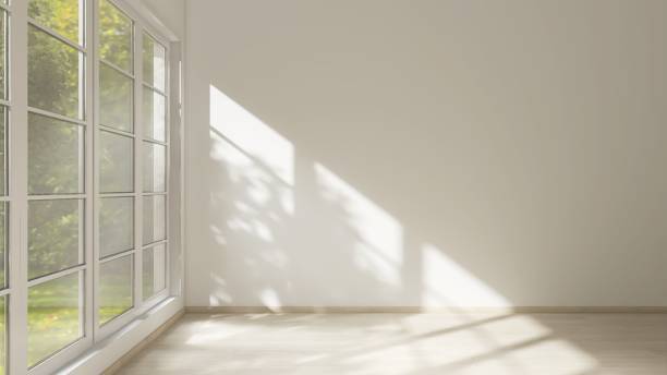 istock Empty room with white wall in sunlight from window, tree shadow on wood laminated floor 2151663387