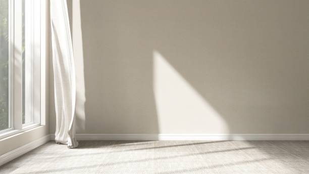 istock Empty room with beige wall in sunlight from window, blowing sheer curtain, shadow on carpet floor 2151663399