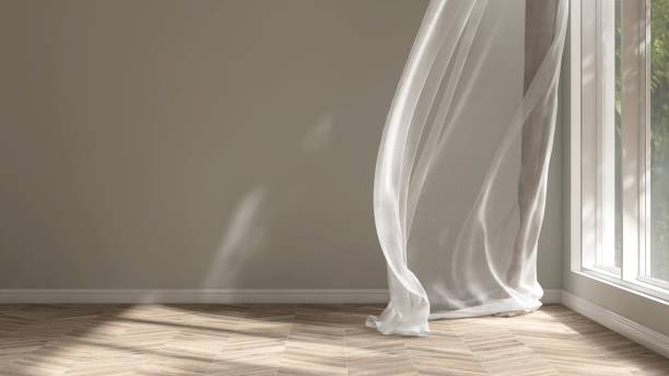 istock Empty beige wall room in sunlight from window, blowing white sheer, brown blackout curtain tree shadow on baseboard, parquet floor 2151663413