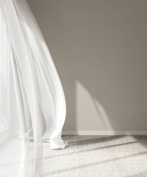 istock Empty room with beige wall in sunlight from window, blowing sheer curtain, shadow on carpet floor 2151663434