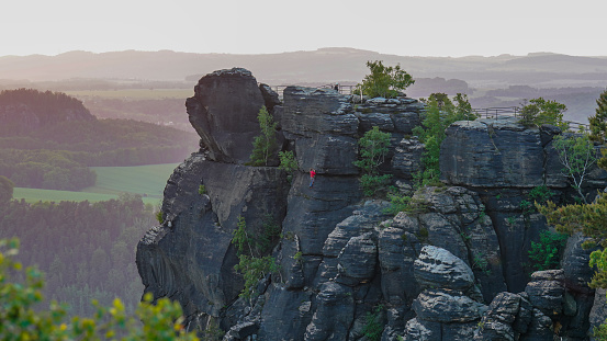 Climbers climb a steep cliff early in the morning. Saxon Switzerland, Germany