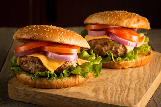 istock Home made hamburger with beef, onion, tomato, lettuce and cheese. Fresh burger close up on wooden rustic table with potato fries, beer and chips. Cheeseburger. 2151663755