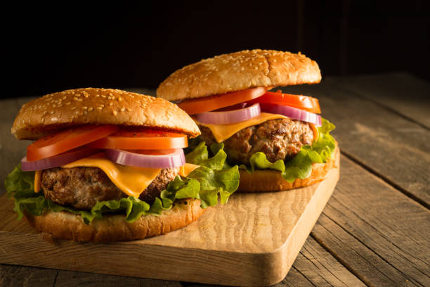 istock Home made hamburger with beef, onion, tomato, lettuce and cheese. Fresh burger close up on wooden rustic table with potato fries, beer and chips. Cheeseburger. 2151663808