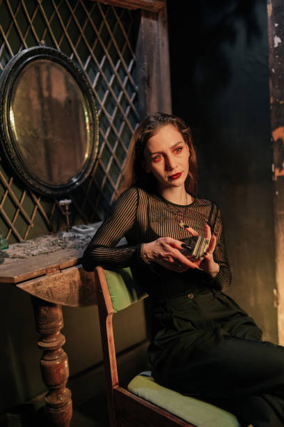 istock Mystery female soothsayer dealing Tarot cards forecasting future for client. Fortune-telling having divination session with tarot cards at dark esoteric room. 2151666309