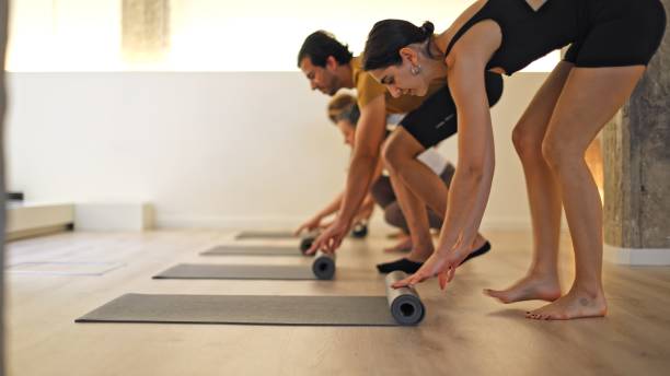 istock Group of four rolling up yoga mats in a modern studio setting. 2151673242