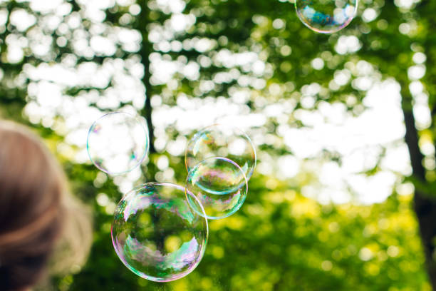 istock child playing with flying soap bubbles, festive atmosphere, sun rays, greenery, fun 2151673270