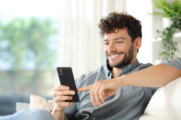 istock Happy man using cell phone on a couch at home 2151674616