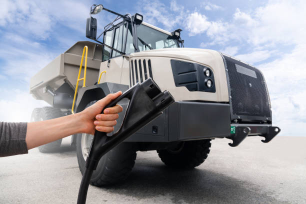istock Hand with charging plug on a background of electric mining truck 2151676706