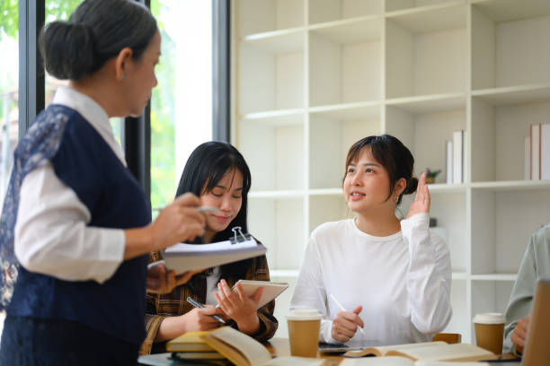 istock Pretty young woman student raising her hand to ask a question during class 2151678449