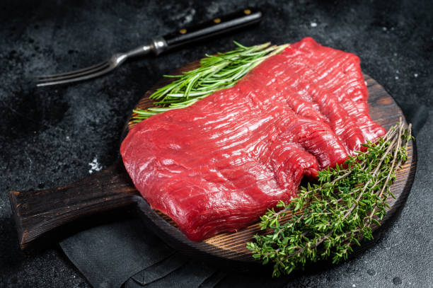 istock Raw flank beef steak, uncooked meat with herbs. Black background. Top view 2151678586
