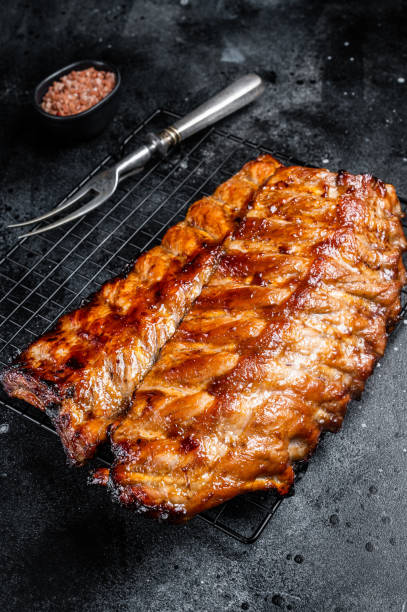 istock BBQ grilled pork spare ribs on a rack. Black background. Top view 2151678626