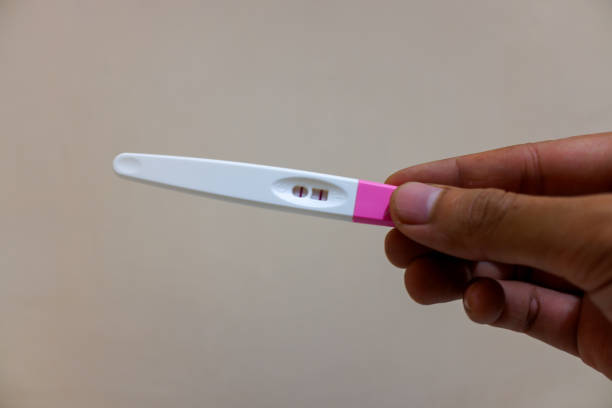 istock Hand holding pregnancy test pack on cream background 2151678690