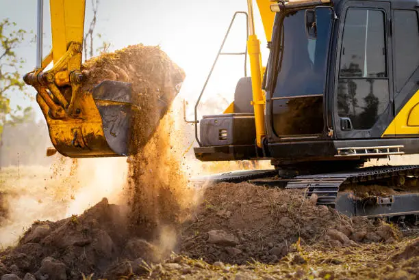 Close-up of excavator at construction site. Backhoe digging soil for earthwork and construction business. Excavating machine at work. Heavy machinery for earth moving and construction site development Close-up of excavator at construction site. Backhoe digging soil for earthwork and construction business. Excavating machine at work. Heavy machinery for earth moving and construction site development