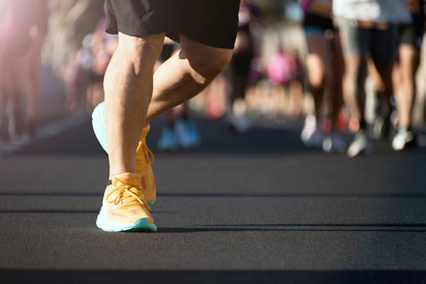 A male runner in an athletic outfit and sunglasses celebrates at the finish line of a race. His arms are outstretched with a joyful expression, embodying determination and achievement.