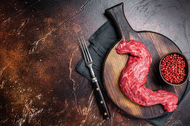 Raw Skirt Machete beef meat steak on wooden board. Dark background. Top view. Copy space