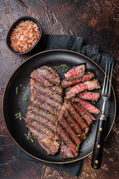 istock Barbecue denver strip beef meat steak on a plate. Dark background. Top view 2151680201