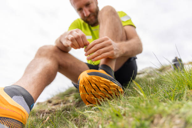 istock Hikers Tying Shoe on Grassy Hill with Overcast Sky 2151680481