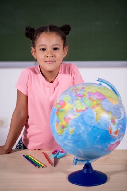 istock african schoolgirl looking globe with chalk background 2151684031