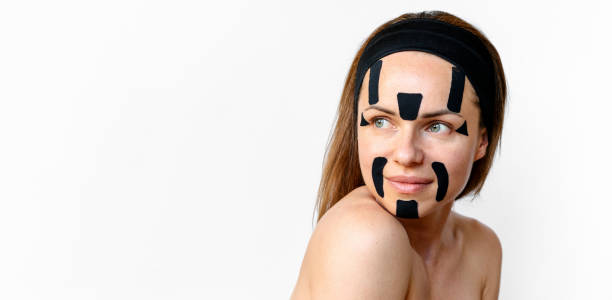 istock Beauty model with kinesio tapes on her face posing in front go white background in studio. skin care and skin improvement concept. 2151684081