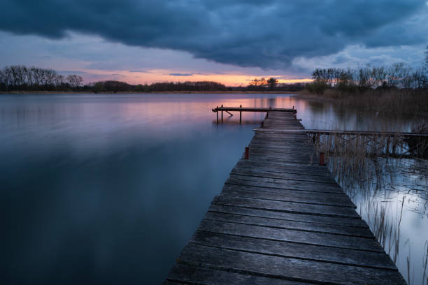 istock Wooden pier on the lake at cloudy sunset, view on a spring evening 2151685899