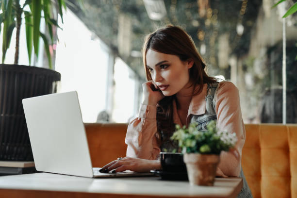 istock Female User Experience Designer Tackling Tough Problems While Working Remotely On Laptop In Coffee Bar 2151686030