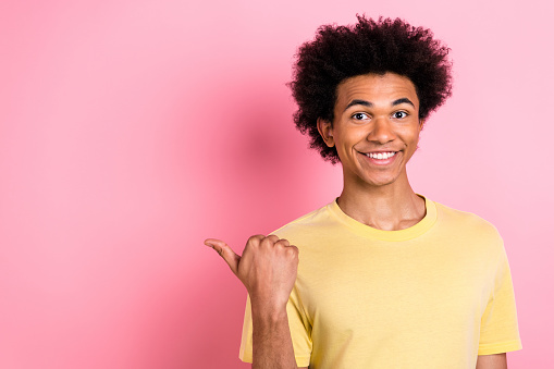 Photo of nice young man indicate finger empty space wear yellow t-shirt isolated on pink color background.