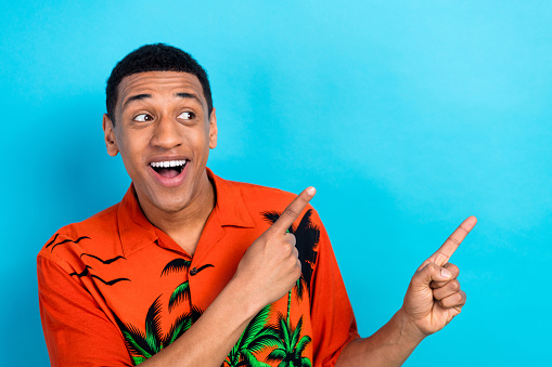 Photo of excited impressed guy dressed print shirt looking showing two fingers empty space isolated blue color background.