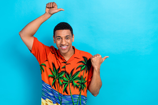 Photo of funky positive guy dressed print shirt showing two thumbs empty space isolated blue color background.