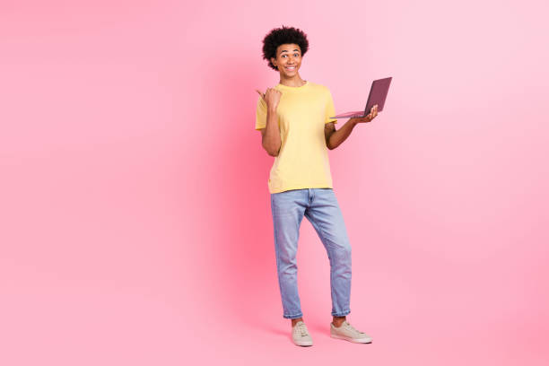 istock Full size portrait of handsome cheerful guy hold netbook indicate finger empty space isolated on pink color background 2151691340