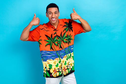 Photo of cool confident guy dressed print shirt showing two thumbs up solated blue color background.