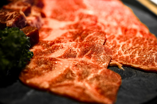 meticulously cut and well-arranged beef with premium marbling alongside fresh green herbs