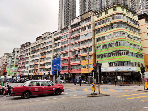 People crossing the street by old fashioned apartment buildings in To Kwa Wan, an area of the eastern shore of Kowloon peninsula. The area belongs to the Kowloon City District of Kowloon.