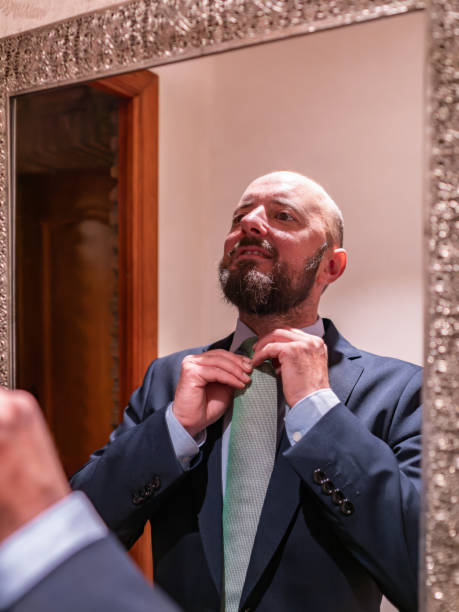 istock Elegant Man Adjusting Green Tie in Mirror 2151694004