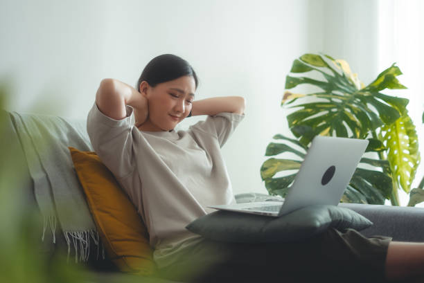 istock Asian woman using laptop suffering from neckache sitting on sofa at home. 2151694516